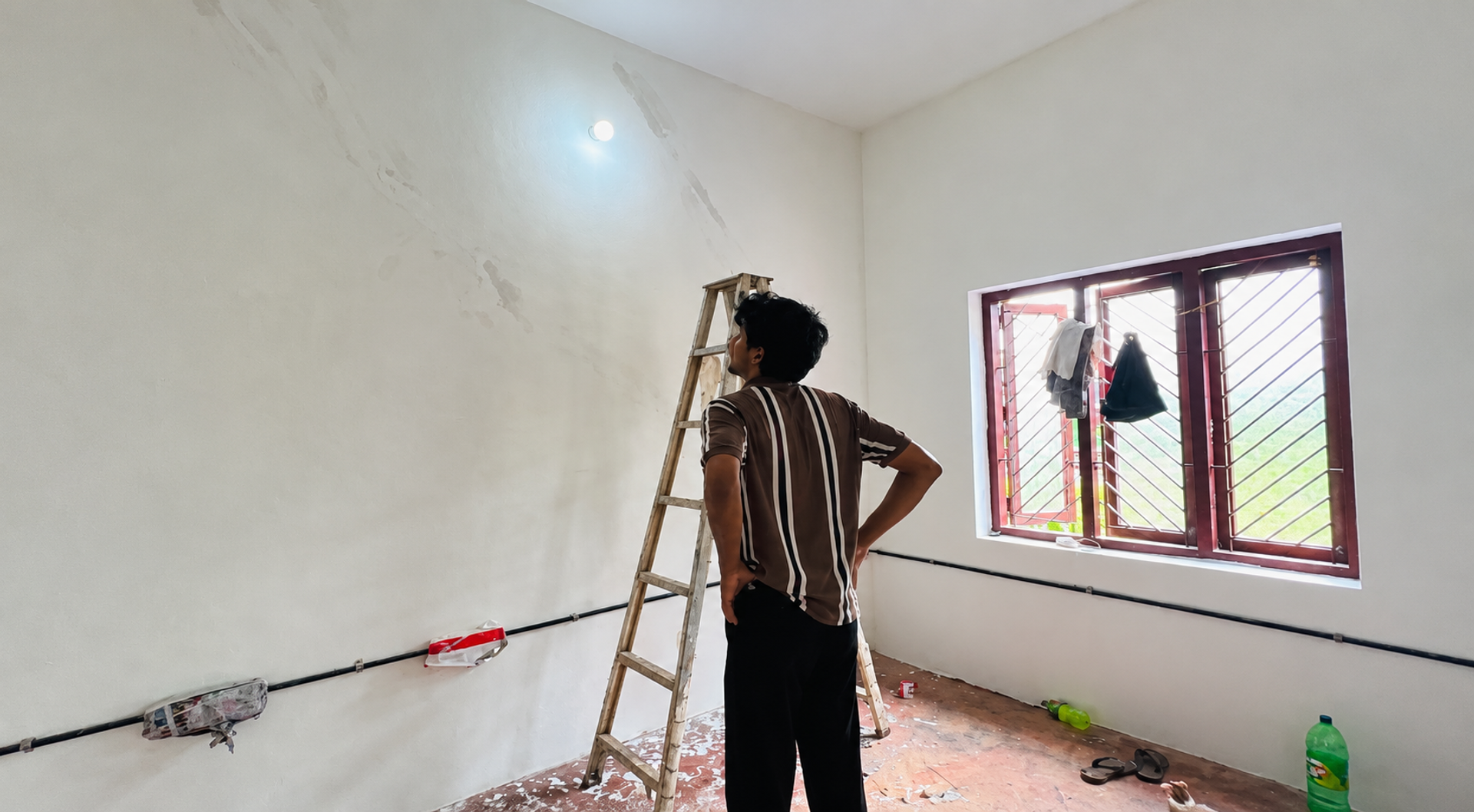 A person in a striped shirt beside a ladder in the unfinished N3 office space