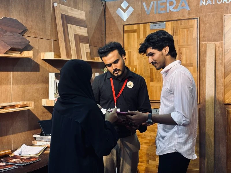Visitors and a VIERA representative looking through a brochure inside the wooden flooring exhibition stall