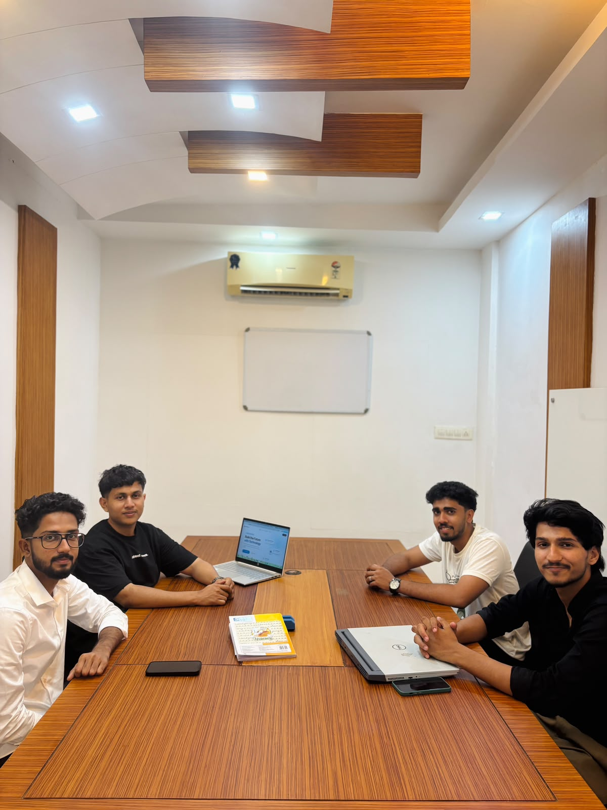 The team gathered around a meeting table with laptops